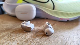 Bose Ultra Open Earbuds in front of Nike trainers