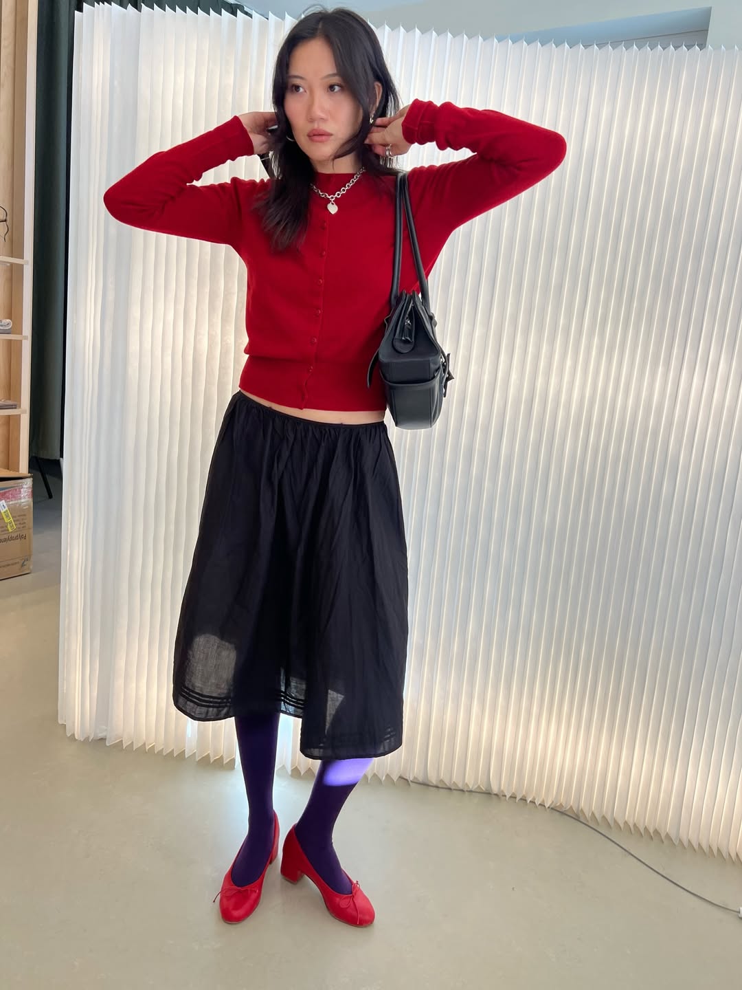 Woman wearing an outfit with red sweater and purple tights.