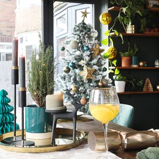 Black kitchen with dining table, Christmas tree and gold tableware and glasses