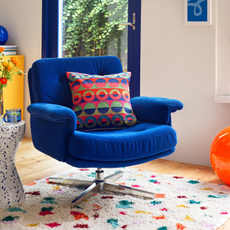 Habitat swivel chsir with bold, retro cushion on a multi-coloured rug.