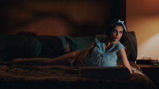 Kaia Gerber as Mitzi, reclining on a sofa, in Palm Royale season 2.