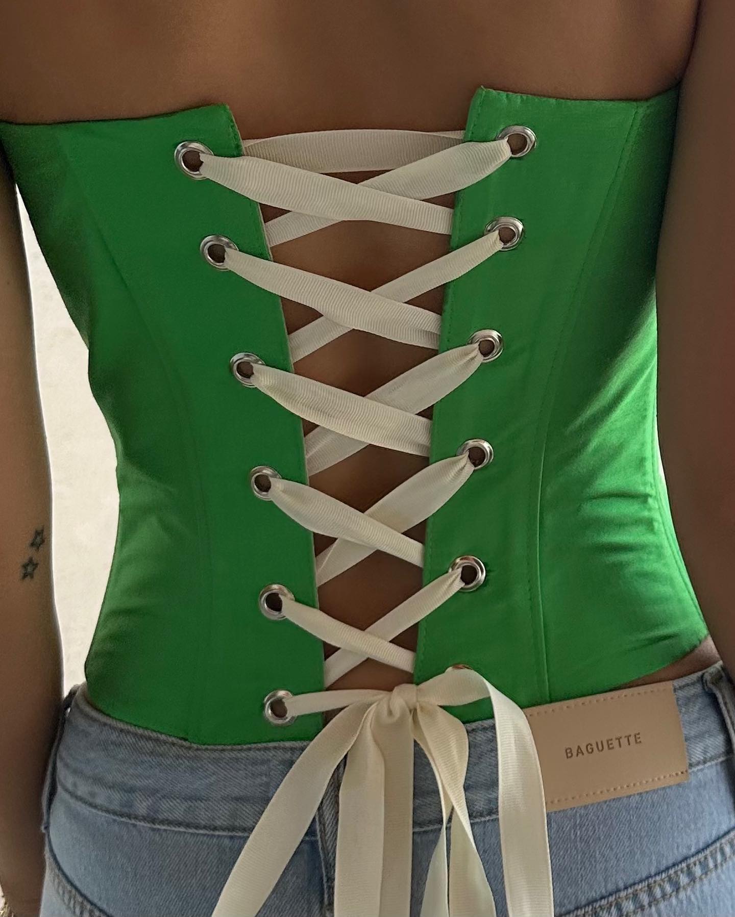A green corset laced up with white ribbon.