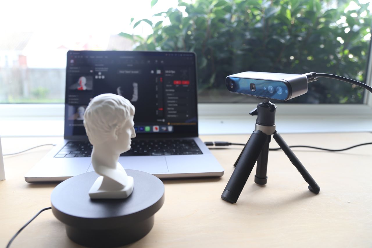 A Revopoint INSPIRE 3D Scanner on a desk, along with an object to scan and a laptop