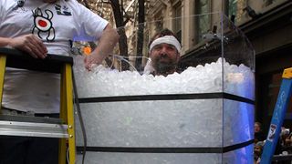 a photo of wim hof (a white man brown hair and a beard) submerged in a huge bucket of ice cubes