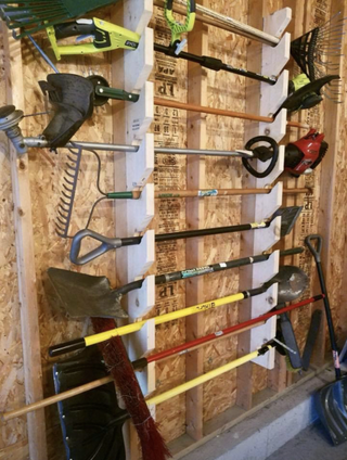 a DIY garage storage rack full of yard essentials such as a spade and a rake