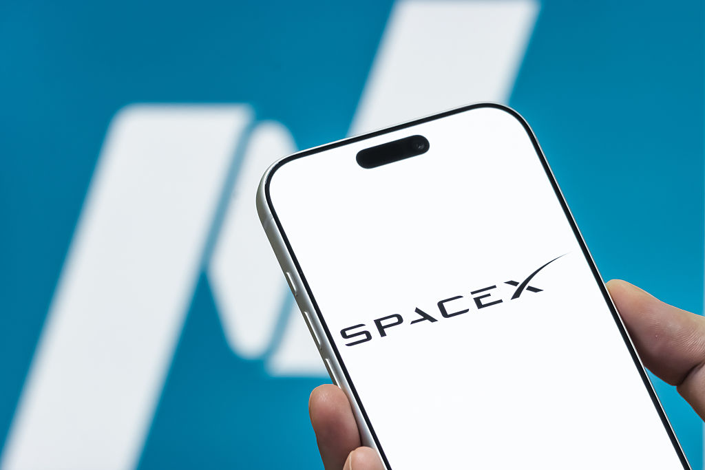 SpaceX logo is seen in front of a blurred Nasdaq logo representing SpaceX's IPO