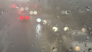 A photo of cars on a London road through the raindrops on a bus window.