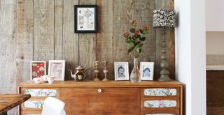 dining room with rustic wood wall paneling and sideboard with old photos and trinkets to show off sentimental items to create a stress-free home