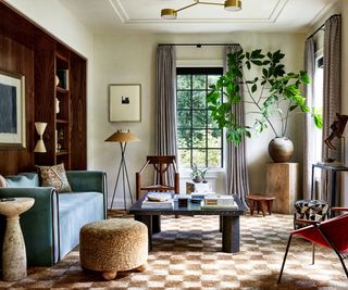 A living room with large windows, wood bookshelves, and a checkered rug