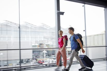 Smiling couple walking through the airport going on holiday with vaccine passports