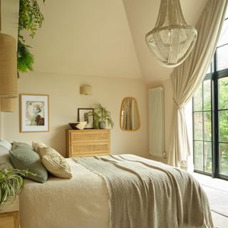 a large main bedroom with double height ceiling and window decorated in a neutral scheme