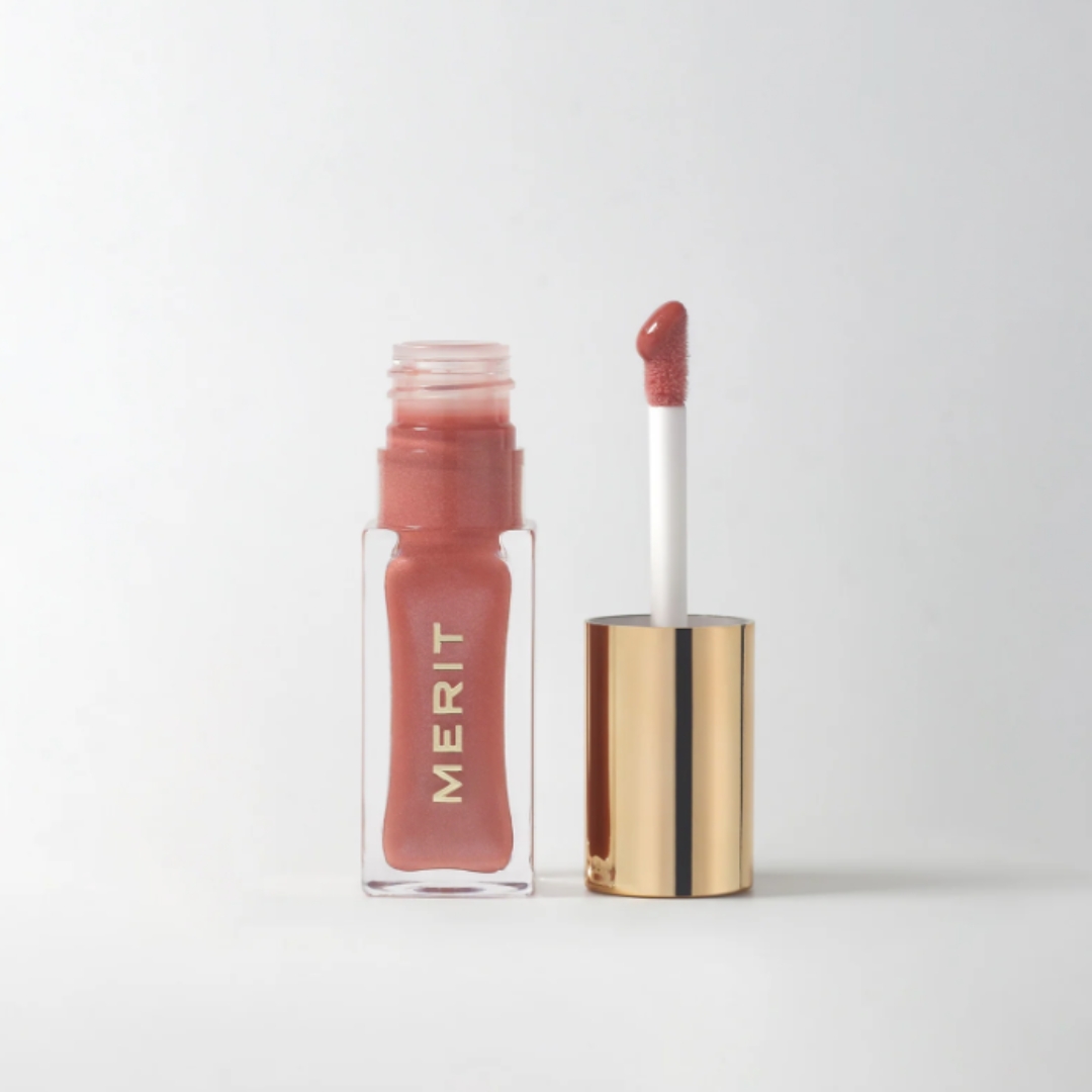 A product shot of the Merit Beauty Shade Slick tinted lip oil in shade Biarritz ( a nude pink), on a grey background