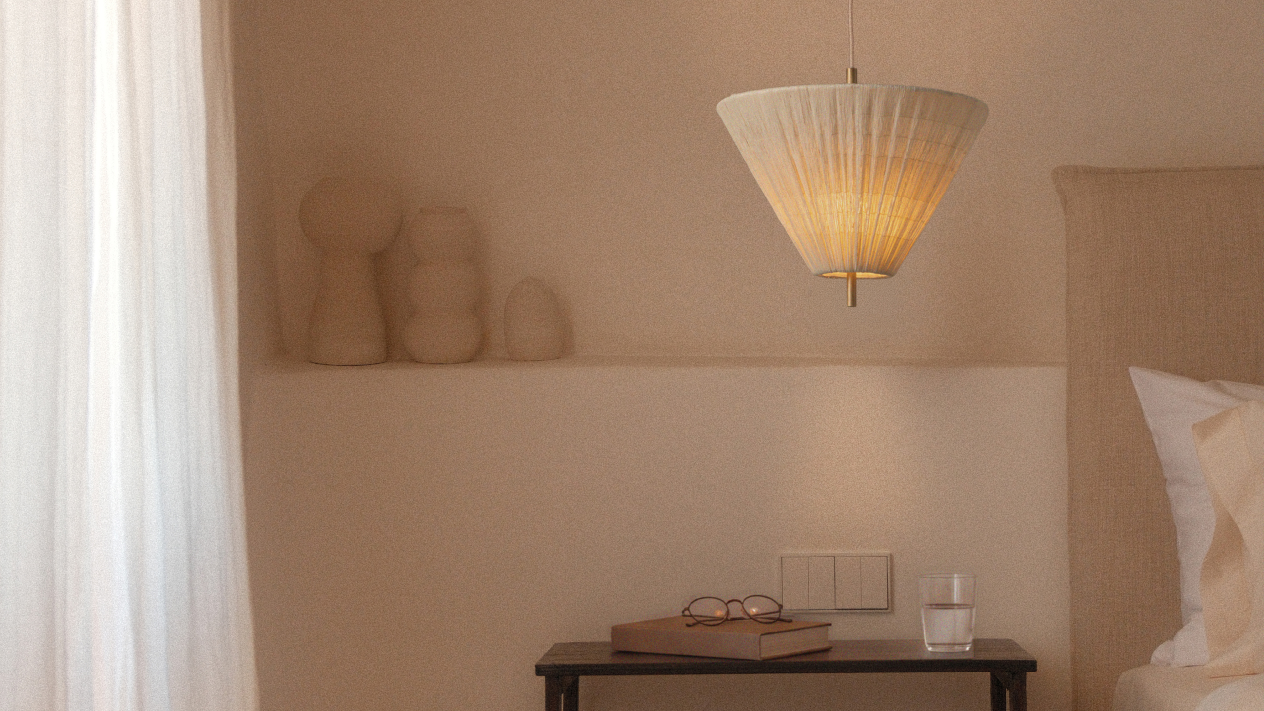 A pendant lamp with a ruched fabric shade from lights&amp;lamps over a wood side table in a minimalist room