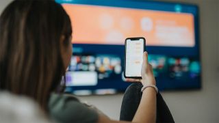 Woman using phone to set up smart tv