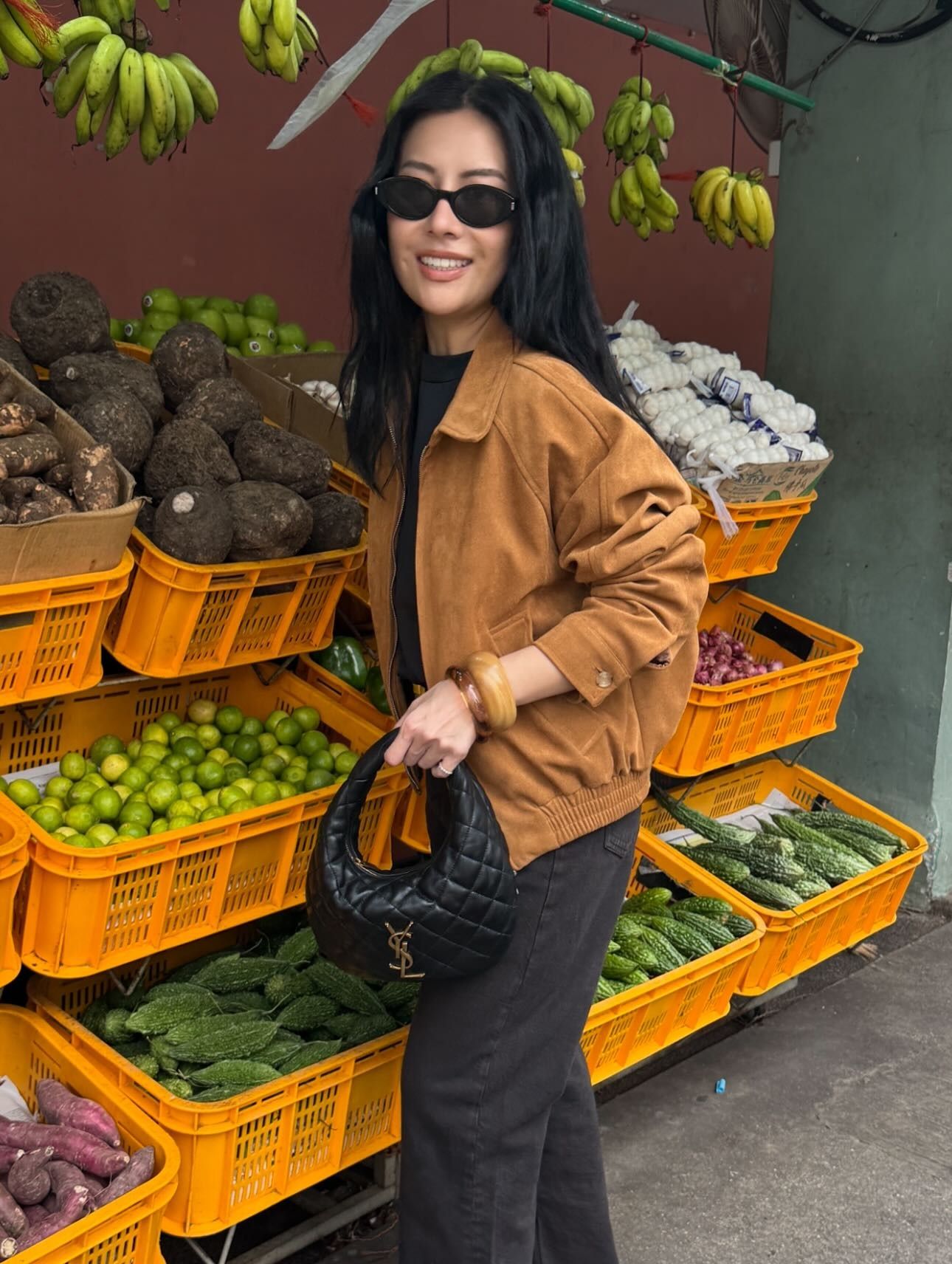 Woman wears brown suede jacket, black jeans and carries Saint Laurent bag