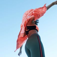 How to run a mile without stopping: A woman running in leggings and a pink raincoat
