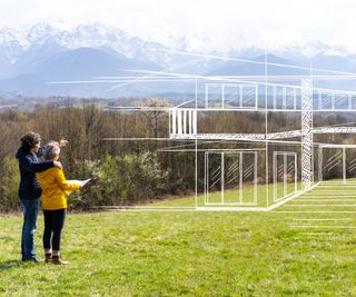 man and woman stood in field with white outline drawing of house drawn on the landscape