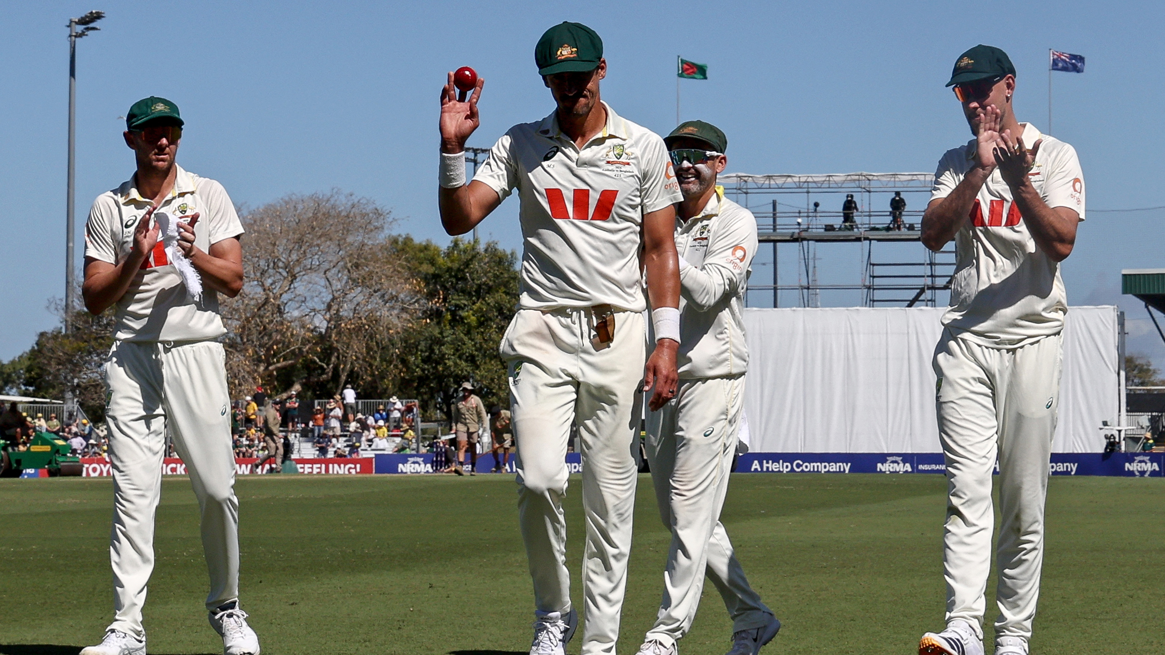 Australia's Mitchell Starc (C) walks off the ground with team mates after taking six wickets for the innings during the first day of the second cricket Test match between Australia and Bangladesh
