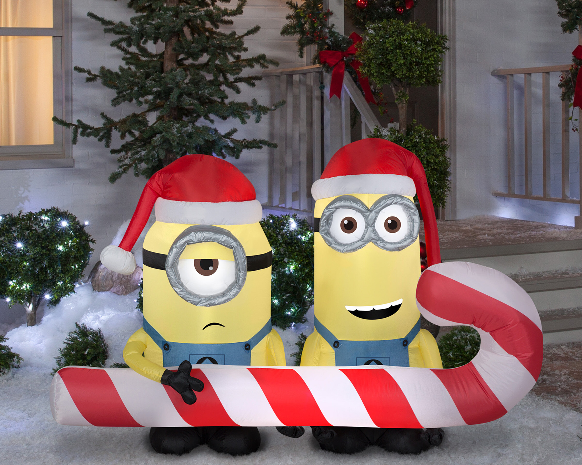Two Minions carrying giant candy cane Christmas inflatable