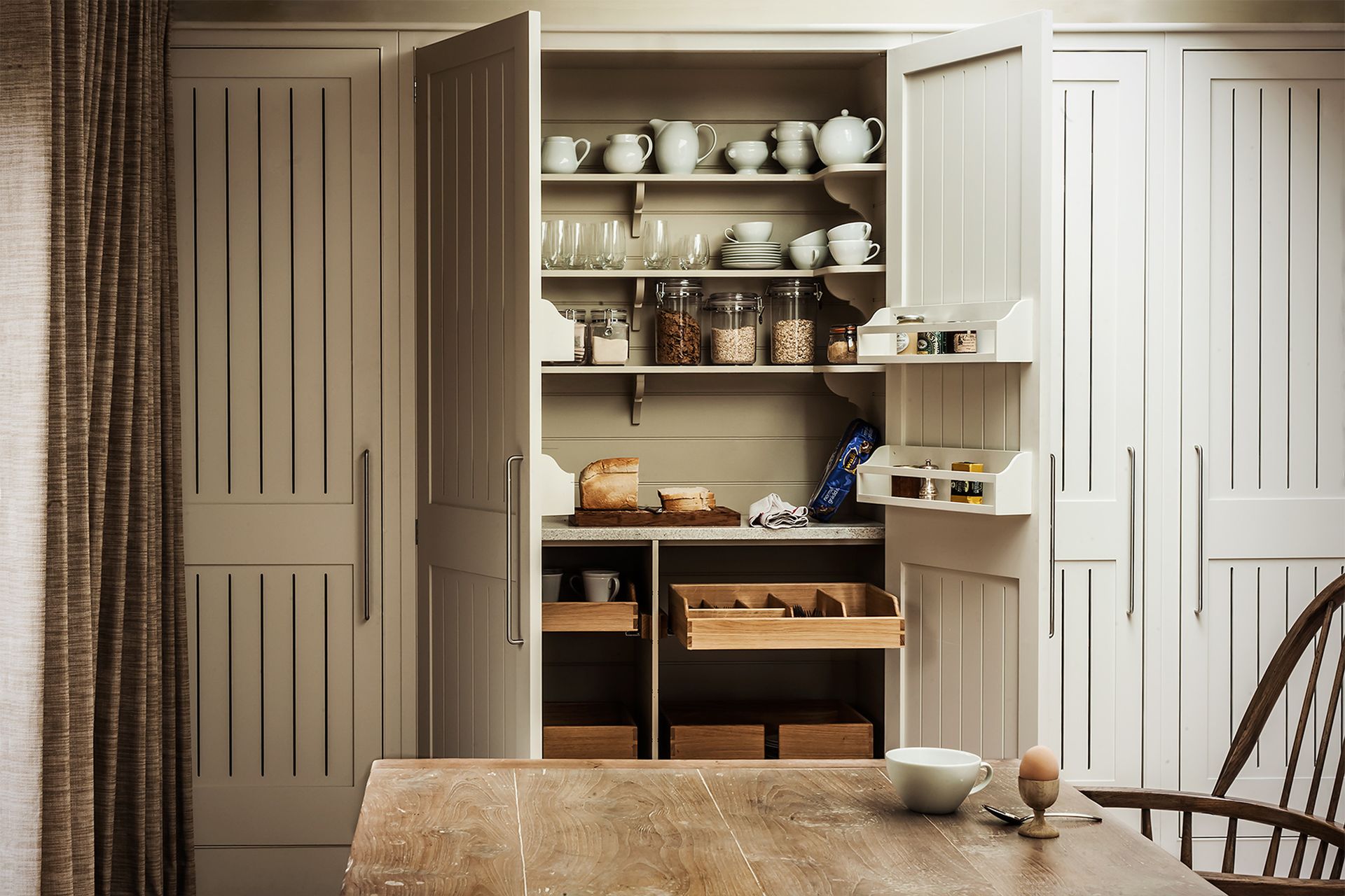 An example of small kitchen storage ideas showing a double pantry hidden behind floor to ceiling cabinet doors