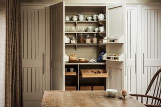 An example of small kitchen storage ideas showing a double pantry hidden behind floor to ceiling cabinet doors