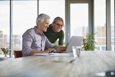 Smiling mature couple using laptop on table at home