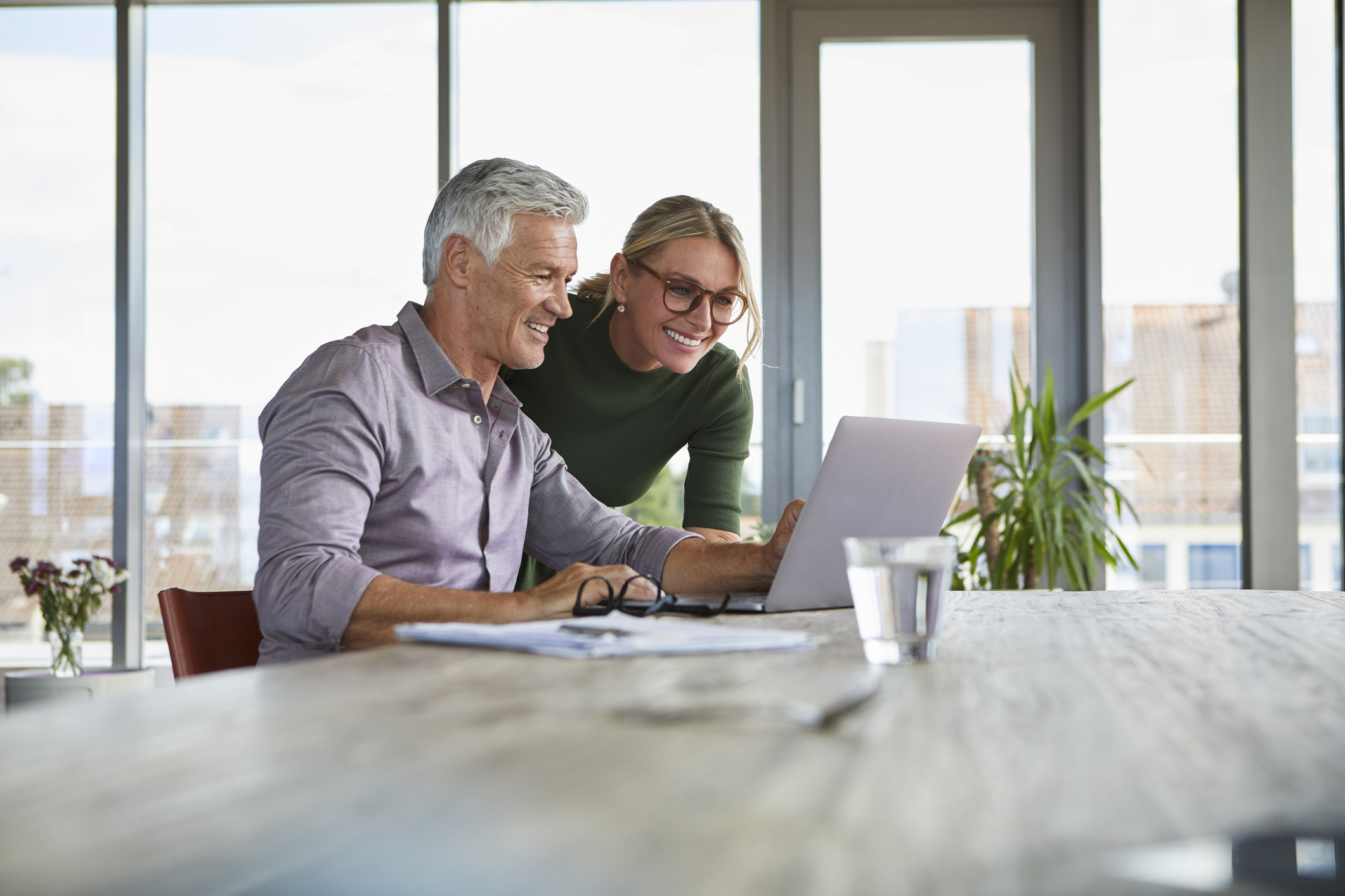 Smiling mature couple using laptop on table at home