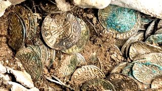 Close up picture of silver coins minted between 1036 and 1044 in England. Some of the coins are bluish-green due to toning over time.