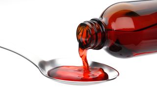 Cough medicine is poured onto a spoon.