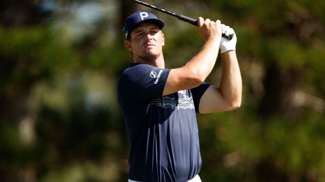 Bryson DeChambeau holds his finish after hitting an iron shot