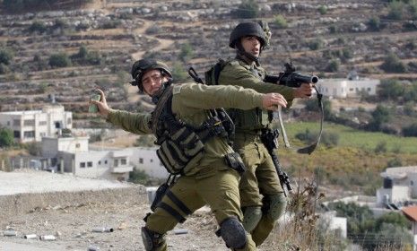 Israeli soldiers throw tear gas at Palestinians protesting military operations against the Gaza strip, in the village of Beit Omar on the West Bank on Nov. 16.