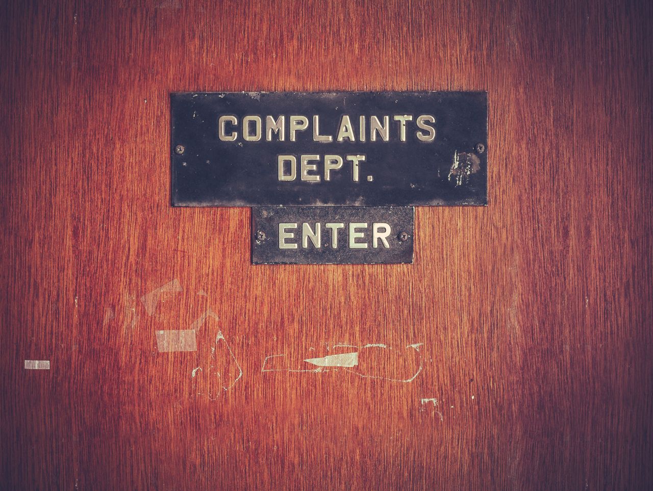 A worn-out door with a sign reading &quot;Complaints Department: Enter&quot;