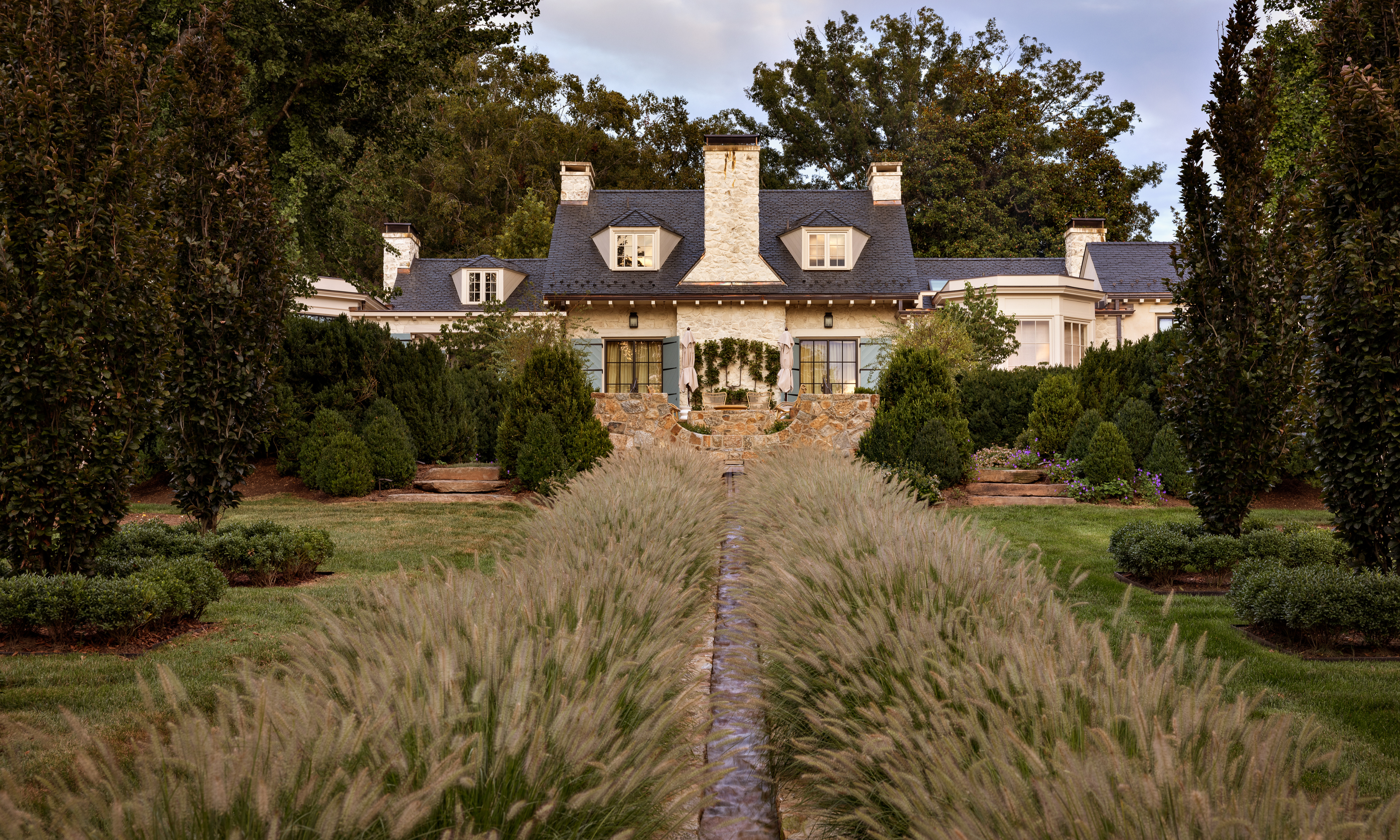 frothy fall grasses bordering rill leading up to large property