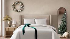 Pure Parima Egyptian cotton sheets on a bed against a beige wall decorated with a wreath and a Christmas tree. 