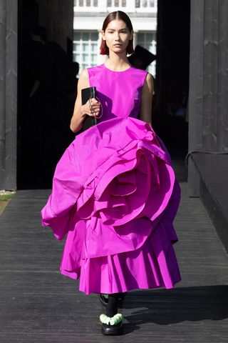 Female model wears Roksanda S/S 2023 on runway - a pink sleeveless dress with a black clutch bag.