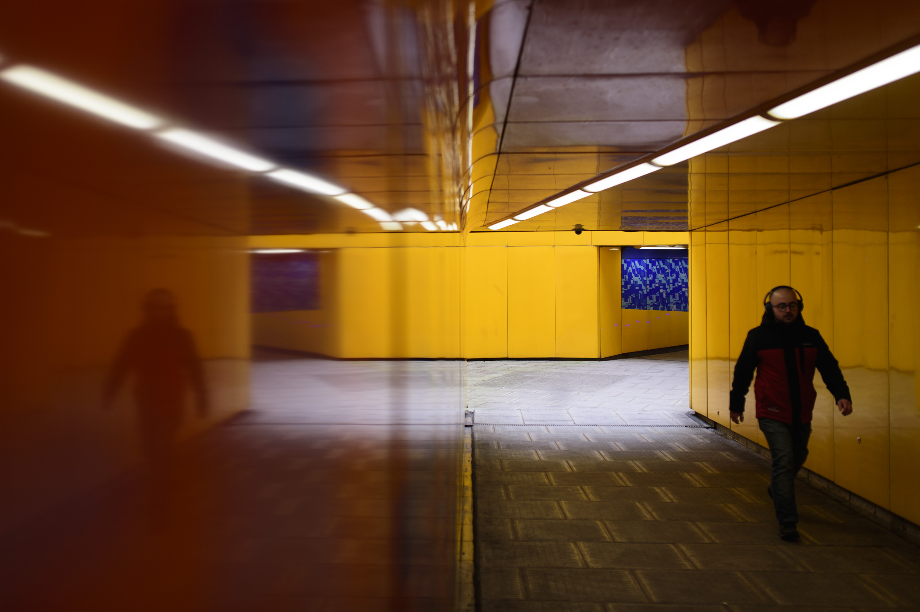 Bright yellow alleyway tunnel, reflected, with person walking