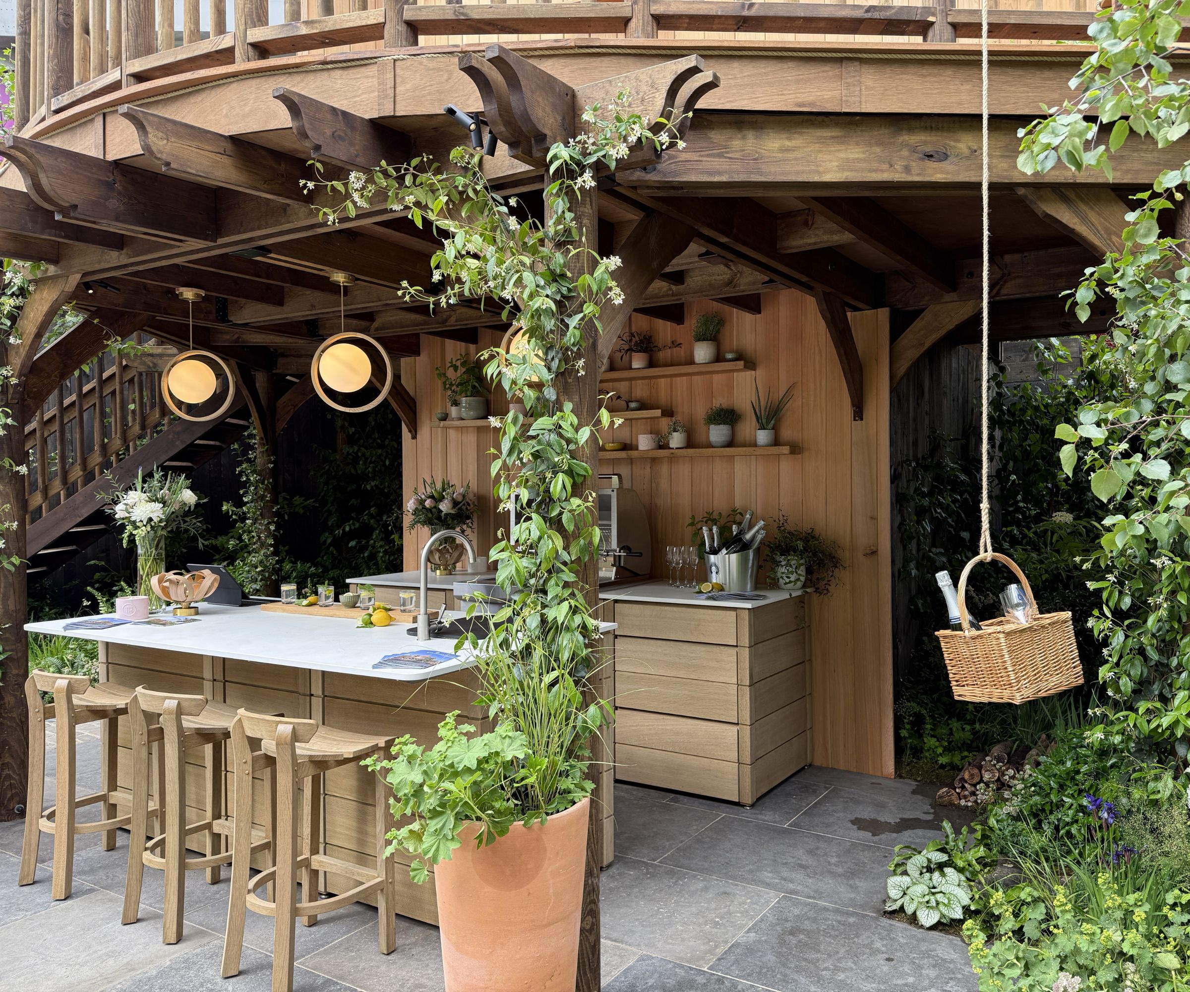 A covered modular outdoor kitchen with wooden cabinets and a white countertop