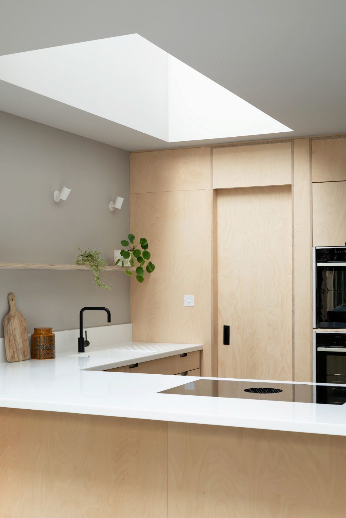 A kitchen with plywood fittings and a rooflight