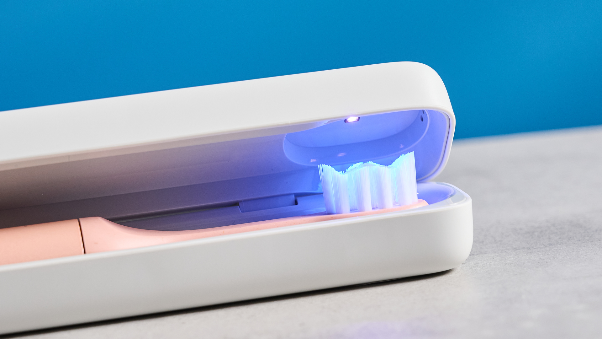 the Suri 2.0 toothbrush in sunset bloom pink colorway with a plant-based head and aluminum body, pictured with its uv cleaning travel case and the suri toothpaste