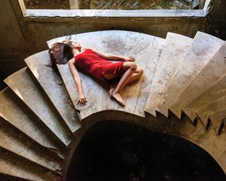 A woman in a red dress lying on spiral staircase