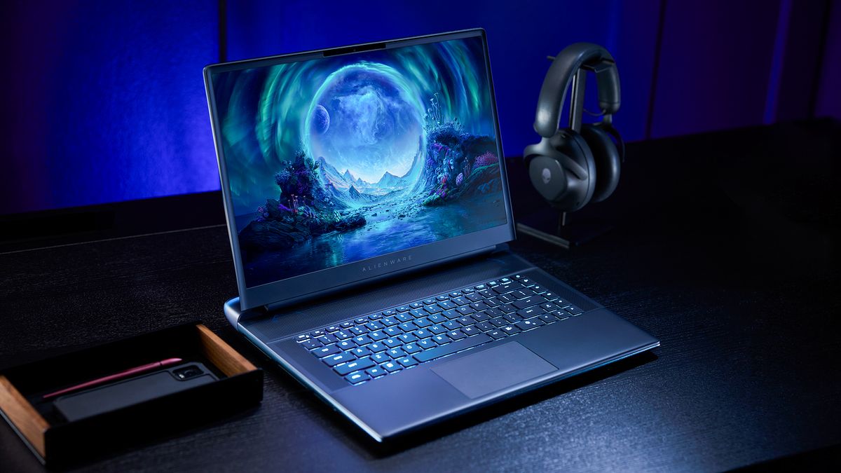 An Alienware Area-51 Laptop on a desk next to a headset and a phone.