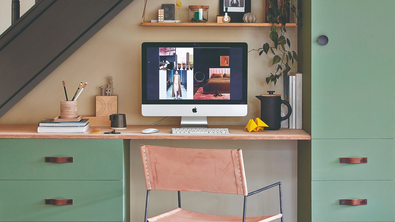 A home office with built-in green cabinets with clean lines and a leather chair