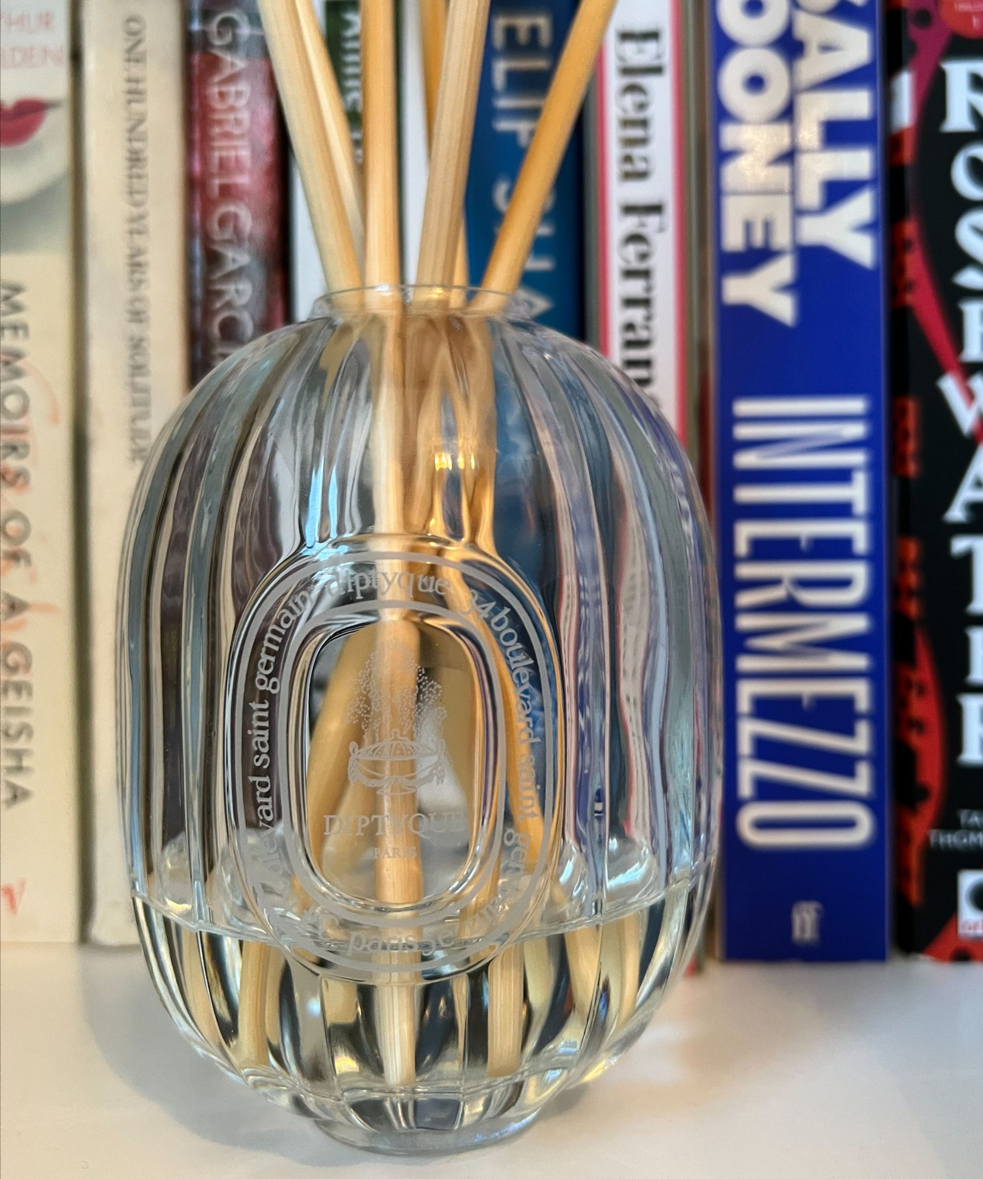 Diptyque Roses Diffuser on a bookshelf against a blurred background of books
