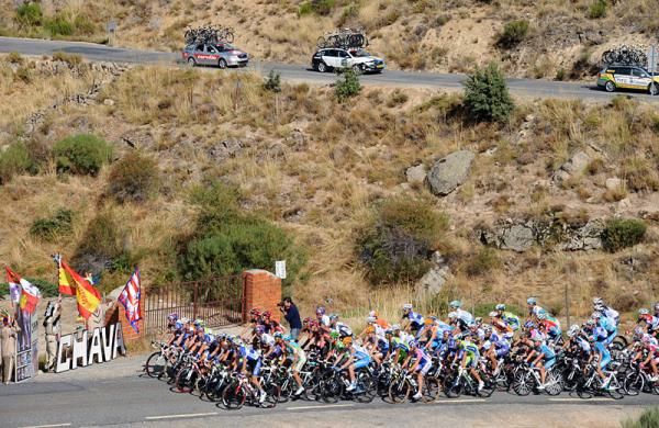 The peloton passes a pocket of fans on an otherwise desolate landscape.