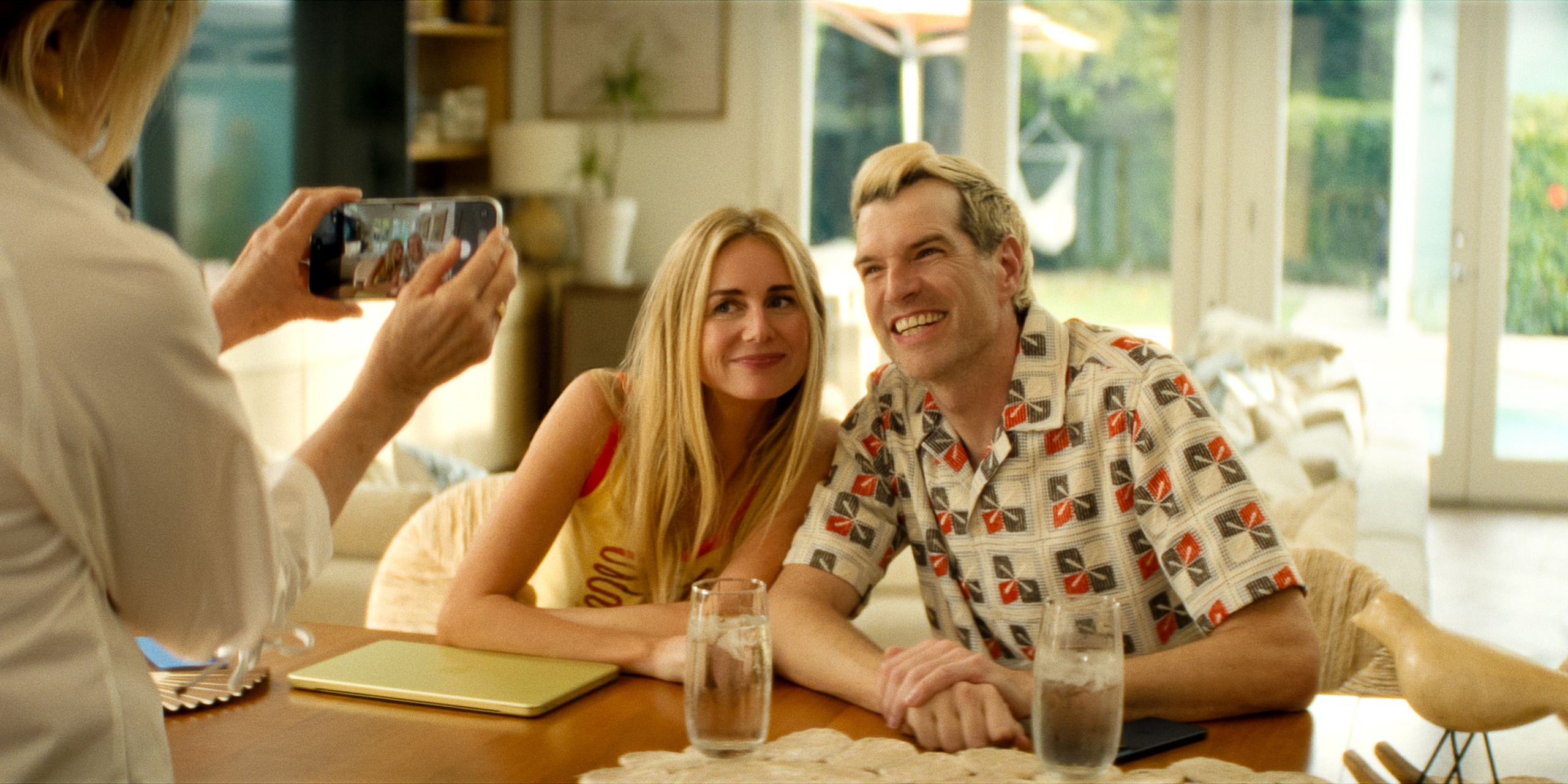 Two blonde adults (Justine Lupe as Morgan and Timothy Simons as Sasha) pose for a picture while sitting in a living room, in episode 306 of #039;Nobody Wants This#039;.