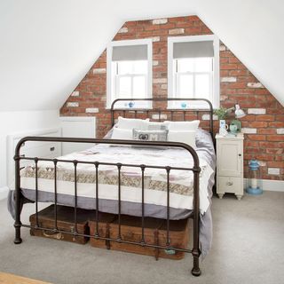 attic bedroom with brick wall and white window and bedside table