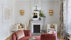 living room with pink tete a tete sofa and fireplace with two white armchairs