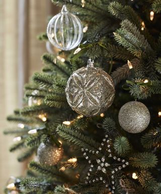 Christmas tree branches with tree ornaments in silver and glass