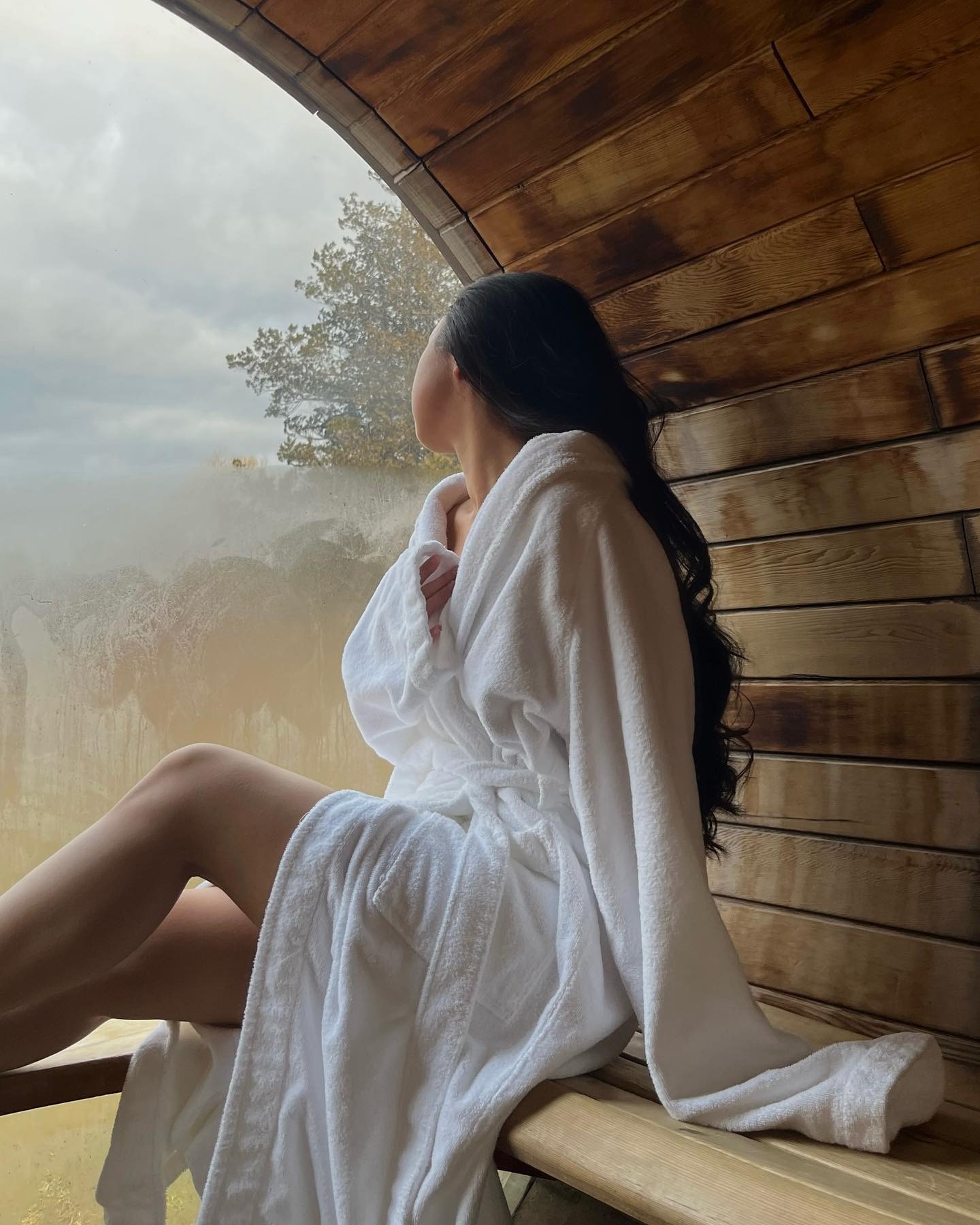 A woman sitting in a sauna wearing a robe