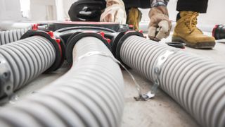 close up of flexible ducting with worker in background fitting it